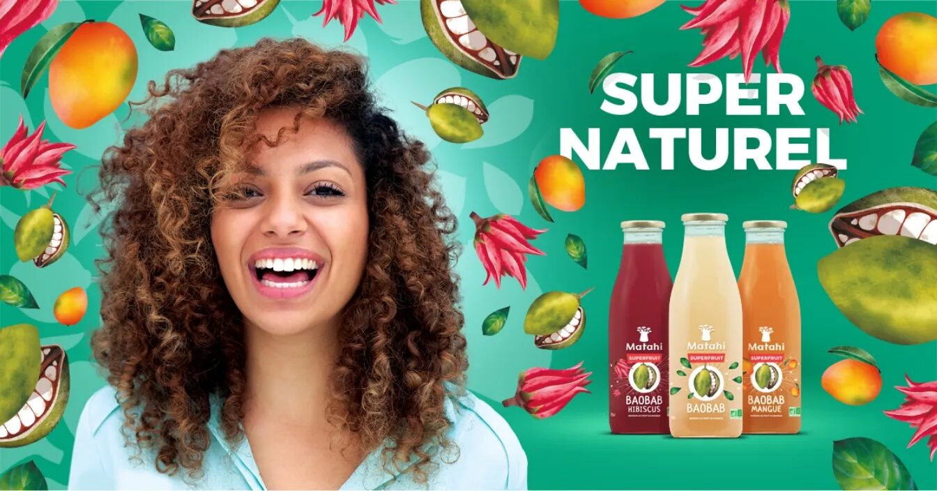 Matathi "Super Natural" advertising visual with a smiling woman, bottles of organic baobab drinks and illustrations of tropical fruits